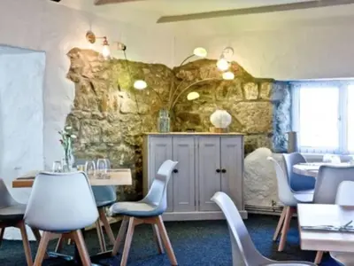 a room with tables and chairs and a stone wall at Chalet Hot Tub Lodge 2 by Interhome in Helston