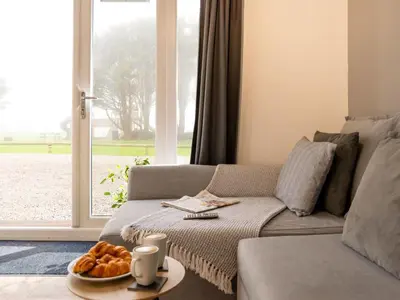 a living room with a couch and a table with bread at Chalet Hot Tub Lodge 2 by Interhome in Helston