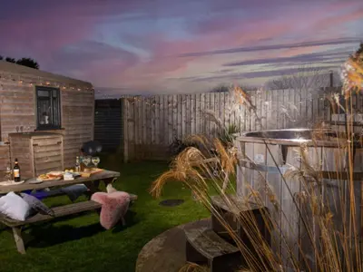 a garden with a table and a bench in the yard at Chalet Hot Tub Lodge 3 by Interhome in Helston
