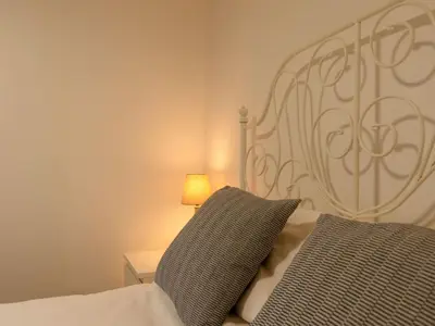 a bedroom with a bed with a headboard and a lamp at Chalet Hot Tub Lodge 3 by Interhome in Helston