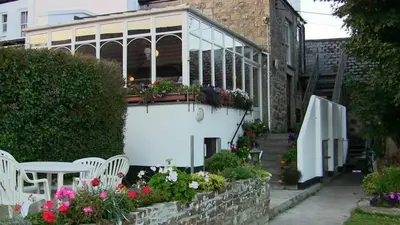 a patio with a table and chairs and flowers at The Badger Inn in Carbis Bay