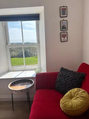 a living room with a red couch and a window at Little Hillside in Porthtowan