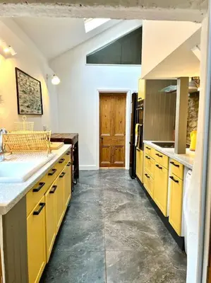 a large kitchen with yellow cabinets and a door at Little Hillside in Porthtowan