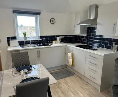 a kitchen with white cabinets and a table and a window at HeyRic in Padstow
