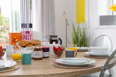a wooden table with breakfast foods and orange juice at Abelia in St Ives