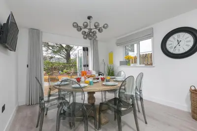 a dining room with a table and chairs and a clock at Abelia in St Ives