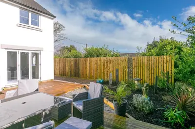 a backyard with a wooden fence and a patio at Abelia in St Ives