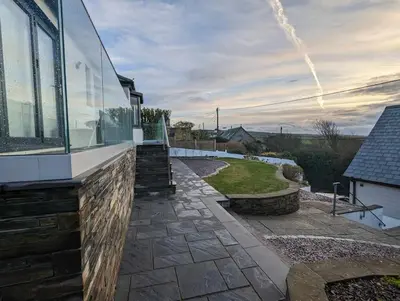 a house with a glass facade and a walkway at Truckle - Treknow, Tintagel - Bungalow in North Cornwall (Sleeps 5 - 7) in Treknow
