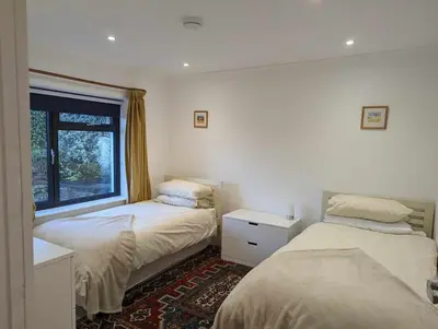 two beds in a room with a window at Truckle - Treknow, Tintagel - Bungalow in North Cornwall (Sleeps 5 - 7) in Treknow