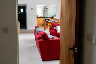 a living room with two red couches and a kitchen at Treworgie Barton - Warner in Bude
