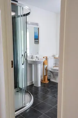 a bathroom with a glass shower and a sink at Treworgie Barton - Warner in Bude