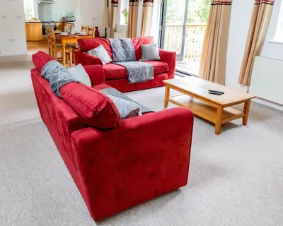 a living room with two red couches and a coffee table at Treworgie Barton - Warner in Bude