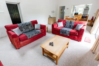 a living room with two red couches and a coffee table at Treworgie Barton - Warner in Bude