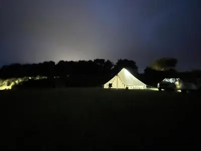 a white tent in a field at night at Trevena Cross Glamping & Camping in Helston