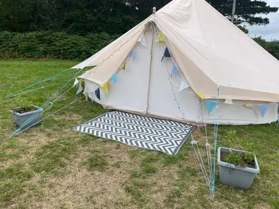 a tent in a field with two potted plants at Trevena Cross Glamping & Camping in Helston