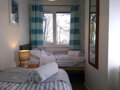 two beds in a room with a mirror and a window at Three bed Holiday Home in Hayle