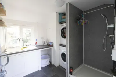 a bathroom with a shower and a sink and a washing machine at Secluded woodland annex between Mylor and Flushing in Falmouth