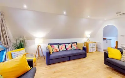 a living room with two blue couches and yellow pillows at St Ives Fir Tree Lodge in St Ives