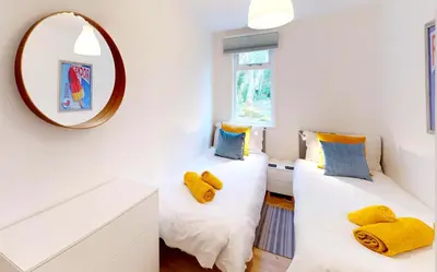 two beds in a room with a mirror at St Ives Fir Tree Lodge in St Ives