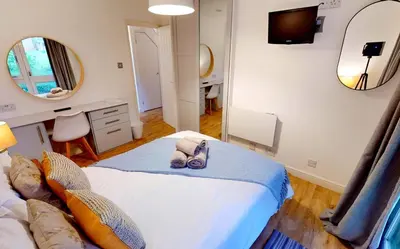 a bedroom with a bed and a mirror at St Ives Fir Tree Lodge in St Ives