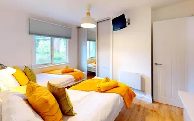 two beds in a room with yellow pillows at St Ives Fir Tree Lodge in St Ives