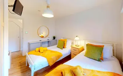 a bedroom with two beds and a mirror at St Ives Fir Tree Lodge in St Ives