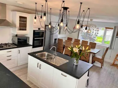 a kitchen with white cabinets and a sink and a table at Wonderful Beach House Just 250m From The Sea in Newquay