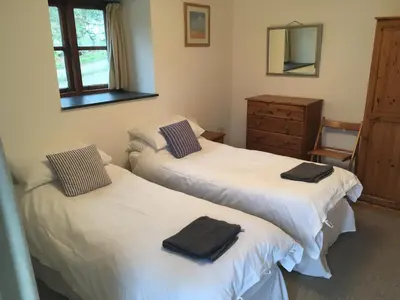 two beds in a room with a dresser and a mirror at Goodrevy Barn in Launceston