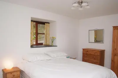 a bedroom with a white bed with a dresser and a window at Goodrevy Barn in Launceston