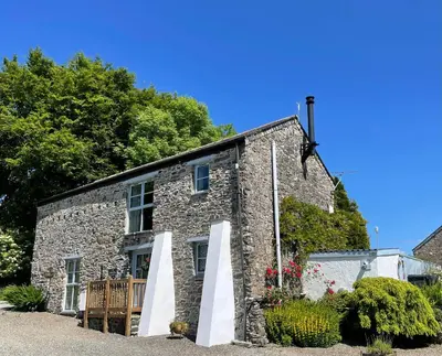 an old stone house with a bench in front of it at Goodrevy Barn in Launceston