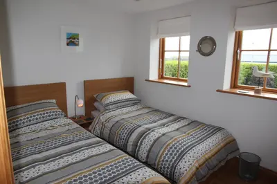 two beds in a room with two windows at Sandbar in Saint Just in Roseland
