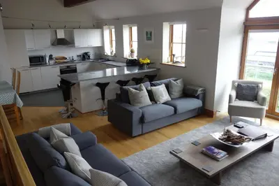 a living room with a couch and a kitchen at Sandbar in Saint Just in Roseland