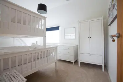 a white bedroom with a bunk bed and a closet at Cornish Cottage - Sleeps 8/9 in Helston