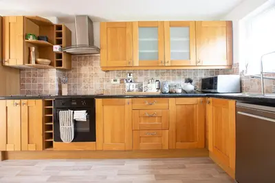 a kitchen with wooden cabinets and a stove top oven at Cornish Cottage - Sleeps 8/9 in Helston