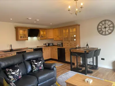 a living room with a couch and a table in a kitchen at Bumblebee Barn, Luxury contemporary holiday home in Perranporth