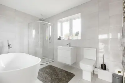 a white bathroom with a tub and a toilet and a sink at Bed and breakfast near Truro and the A30 in Truro