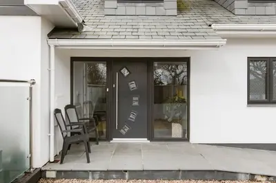 a white house with a black door and chairs at Bed and breakfast near Truro and the A30 in Truro