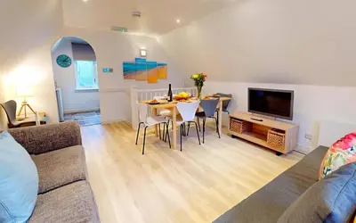 a living room with a table and a television at St Ives Bluebell Cottage in St Ives