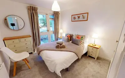 a bedroom with a bed and a chair and a mirror at St Ives Bluebell Cottage in St Ives
