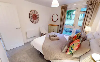 a bedroom with a couch and a clock on the wall at St Ives Bluebell Cottage in St Ives