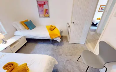 a small bedroom with two beds and a chair at St Ives Bluebell Cottage in St Ives