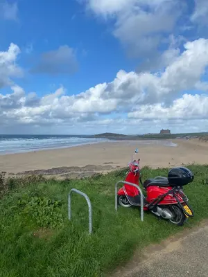 a red scooter parked on the side of a beach at Cosy Cornish cottage with rural views in Newquay