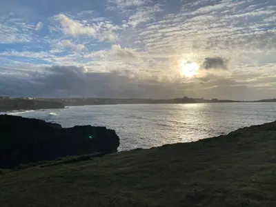 a view of a body of water with the sun setting at Cosy Cornish cottage with rural views in Newquay