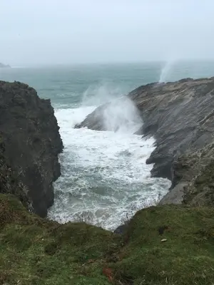 a body of water next to the ocean with waves at Cosy Cornish cottage with rural views in Newquay