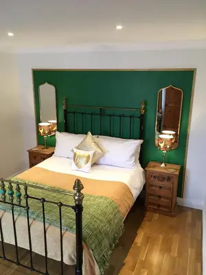 a bedroom with a large bed with a green headboard at Number Six in St. Agnes