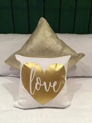 a gold heart pillow with the word love on it at Number Six in St. Agnes