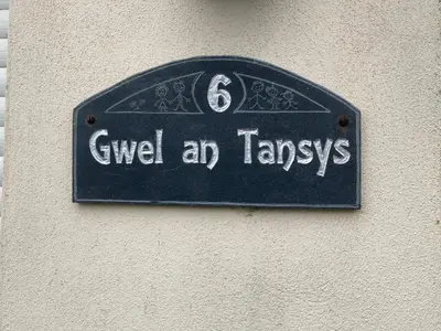 a sign on a wall that says give a taxi at Number Six in St. Agnes