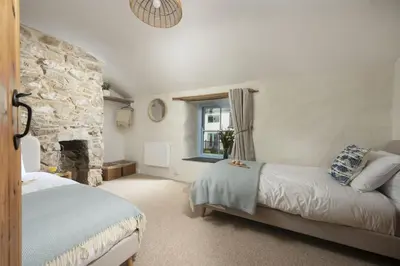 a bedroom with two beds and a stone fireplace at School Cottage, Marazion in Marazion