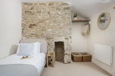 a bedroom with a stone wall with a bed and a stone fireplace at School Cottage, Marazion in Marazion