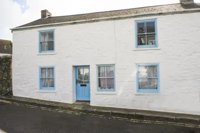 a white house with blue windows and a blue door at School Cottage, Marazion in Marazion